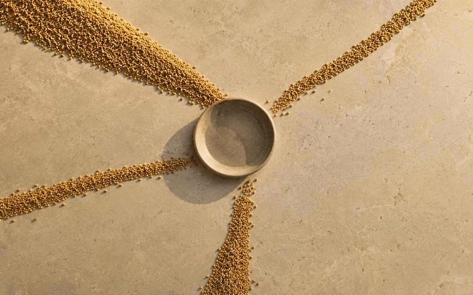 Four trails of grain converging into one shallow bowl from four directions, one of the four visibly thicker than the rest.